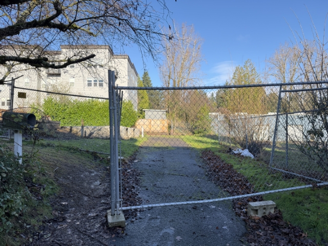 Cleared and fenced parcel at Barbur Apartments site in SW Portland after demolition of 1927-built single-family home.