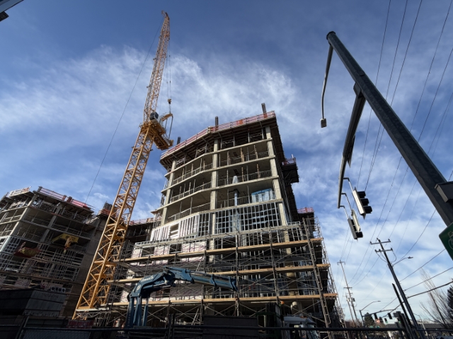 Low-angle view of hollywoodHUB 12-story affordable housing facade under construction, showing curved corner and height at Hollywood Transit Center, Portland – January 12, 2026.